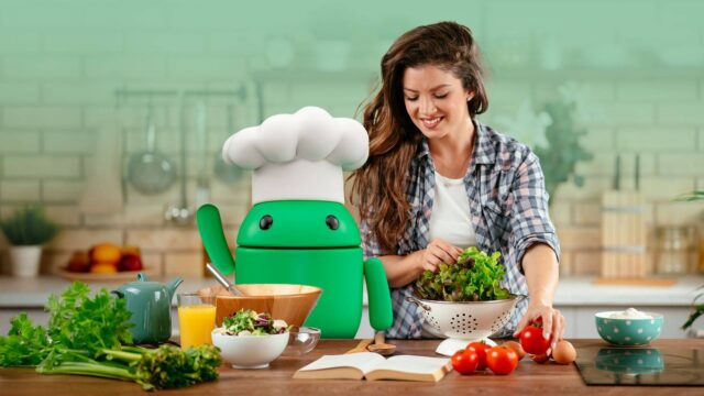 smiling-woman-preparing-a-salad-in-a-kitchen-beside-the-android-mascot-wearing-a-chef-hat-surrounded-by-fresh-vegetables-and-cooking-items.jpg